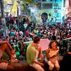 People attend a samba concert in the area of Quilombo Pedra do Sal, backdropped by a graffiti depicting Zumbi Dos Palmares - the main leader of Quilombo dos Palmares in Alagoas state during the colonial period and who became a symbol of the fight against slavery in the country- in downtown Rio de Janeiro, Brazil on December 18, 2017. .In Rio de Janeiro, three communities of descendants of slaves who broke chains from their masters cultivate the memory of their ancestral struggle. Unlike other "quilombos", they are amid the city and their current fight is against real estate speculation. / AFP PHOTO / MAURO PIMENTEL (Photo credit should read MAURO PIMENTEL/AFP via Getty Images)
899383338
TOPSHOTS, Horizontal, CROWD, SAMBA, CONCERT, EFFIGY, SLAVERY
People attend a samba concert in the area of Quilombo Pedra do Sal, backdropped by a graffiti depicting Zumbi Dos Palmares - the main leader of Quilombo dos Palmares in Alagoas state during the colonial period and who became a symbol of the fight against slavery in the country- in downtown Rio de Janeiro, Brazil on December 18, 2017. In Rio de Janeiro, three communities of descendants of slaves who broke chains from their masters cultivate the memory of their ancestral struggle. Unlike other "quilombos", they are amid the city and their current fight is against real estate speculation. Rights managed: Full editorial rights UK, US, Ireland, Italy, Spain, Canada (not Quebec)